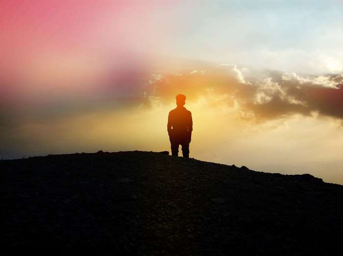 Silhouette of a man standing on a hill at sunset 4K