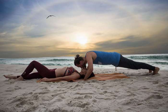 Couple doing yoga on the beach at sunset