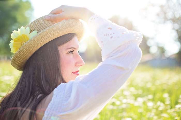 Woman in a straw hat with flowers in a sunny field