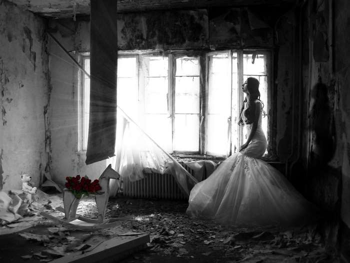 Woman in wedding dress in abandoned room with rocking horse