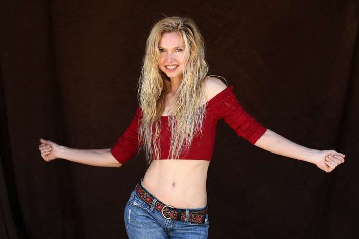 A happy woman in a red crop top and jeans
