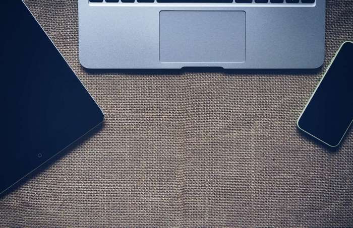 Apple laptop, tablet, and smartphone on a burlap surface