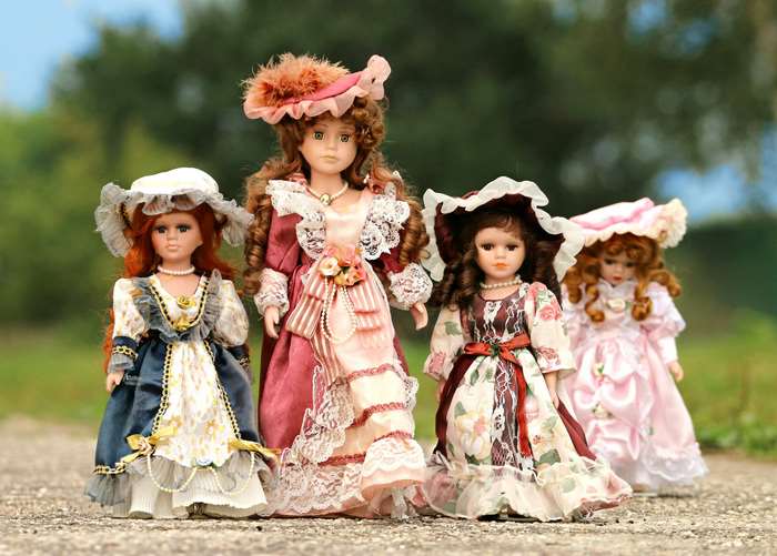 Four porcelain dolls in vintage dresses outdoors