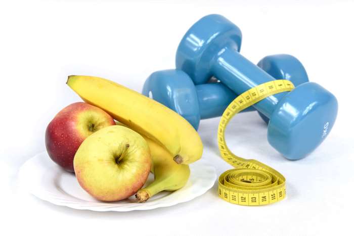 Dumbbells, fruit, and measuring tape for fitness