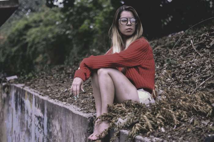 Woman in red sweater sitting on a wall
