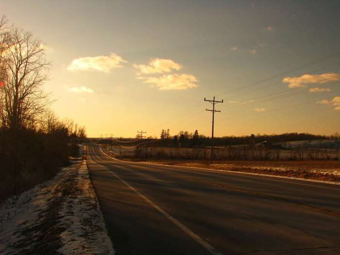 Country road at sunset with snow and trees