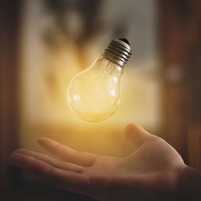 Light bulb levitating above a hand