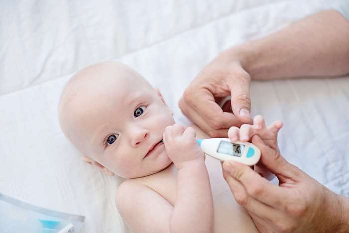 Baby having temperature taken with thermometer