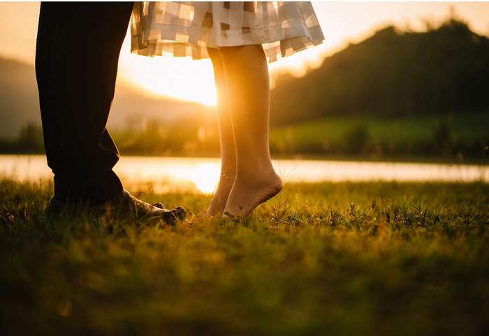 Couple's feet in grass at sunset