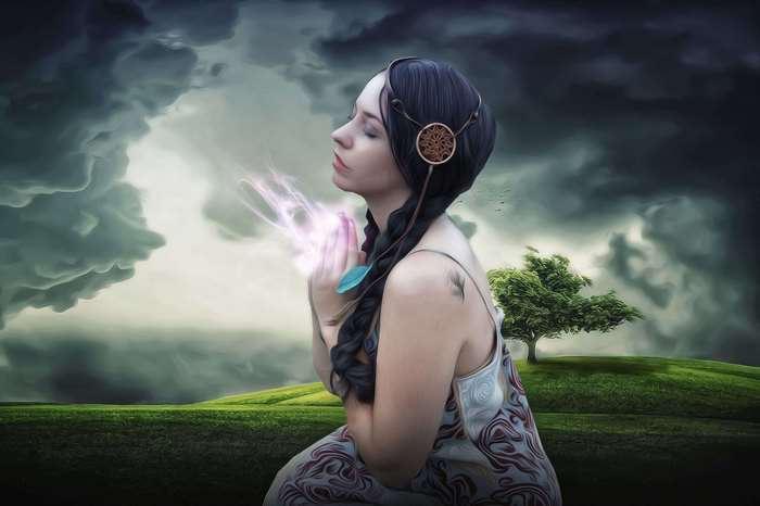 Woman praying with magical energy in a stormy landscape