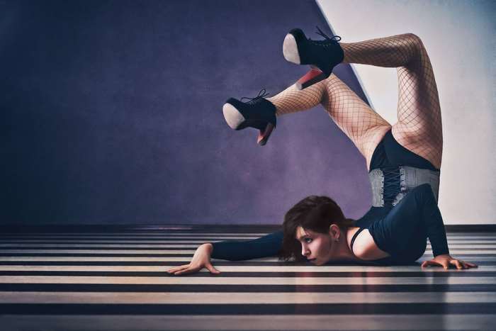 Dancer in corset and fishnet stockings performing a contortion pose