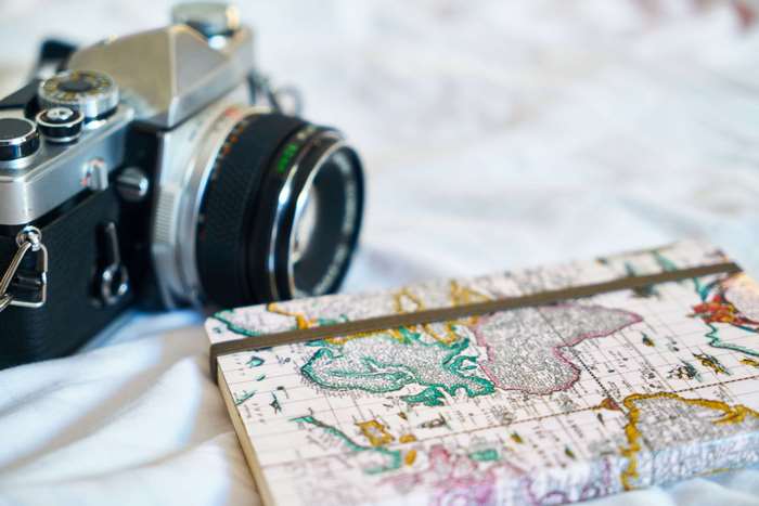 Vintage camera and map notebook on white fabric