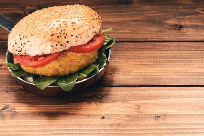 Vegetarian burger with tomato and spinach on a wooden table