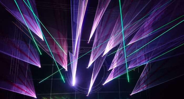 Laser show with purple and green lights at a festival