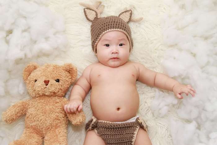 Baby in deer costume with teddy bear