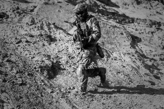 Soldier in uniform with rifle in desert terrain