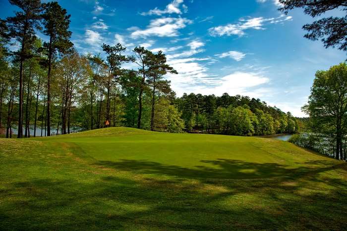 Golf course with a lake and trees under a blue sky
