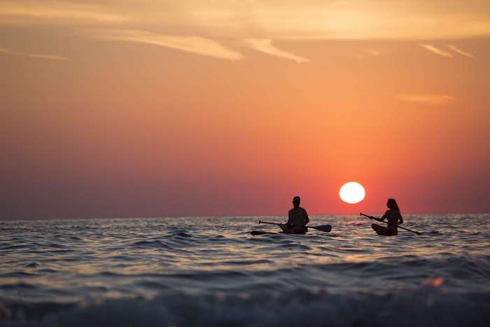 Couple paddleboarding at sunset 4K