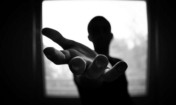 Silhouette of a man reaching out his hand