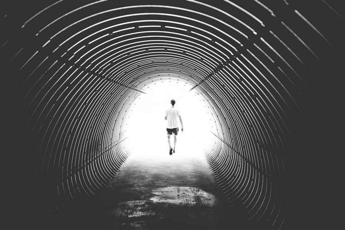 Man walking through a black and white tunnel towards light 4K