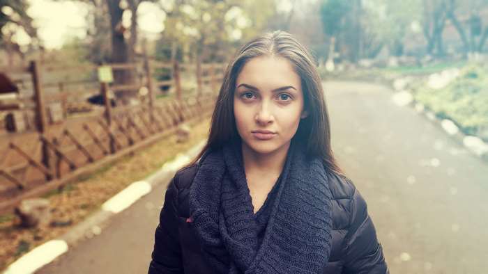 Young woman in a park wearing a scarf and jacket