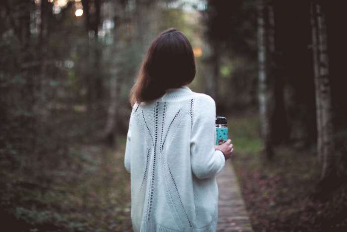 Woman holding thermos walking in forest 4K