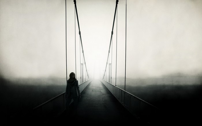 Woman walking on a foggy suspension bridge