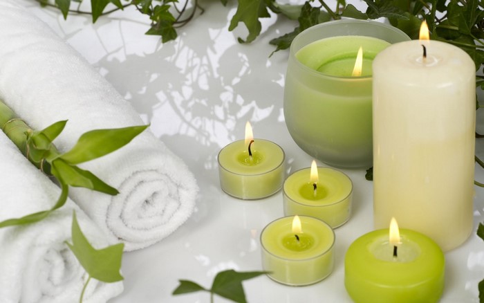 Spa setting with rolled towels, bamboo, and lit candles