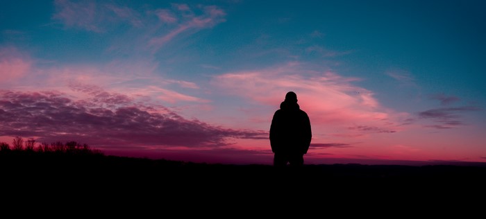 Silhouette of a man against a colorful sunset sky