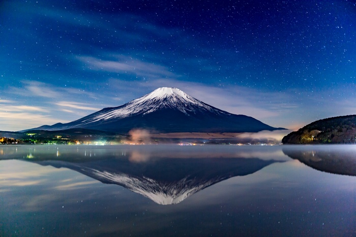 Mount Fuji reflected in a lake at night under stars