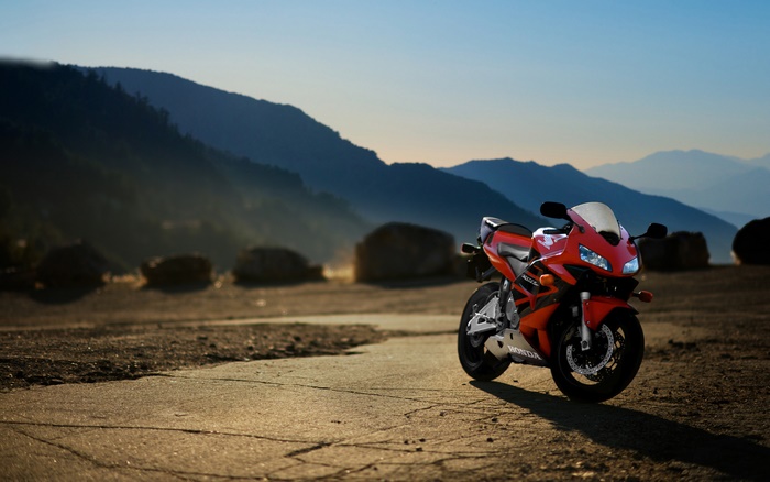 Red Honda CBR motorcycle on a dirt road with mountains