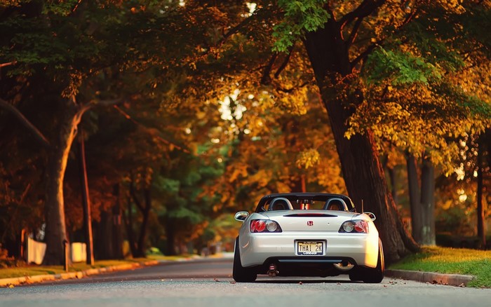 Silver Honda S2000 convertible parked on a tree-lined street