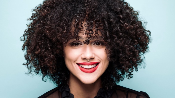 Nathalie Emmanuel with curly black hair and red lipstick