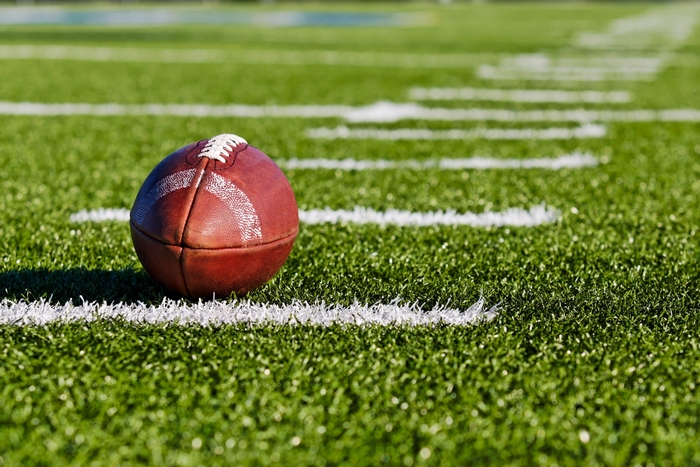 American football on a grassy field with yard lines