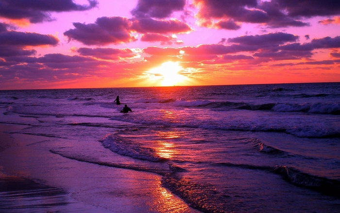 Sunset over the ocean with two people in the water