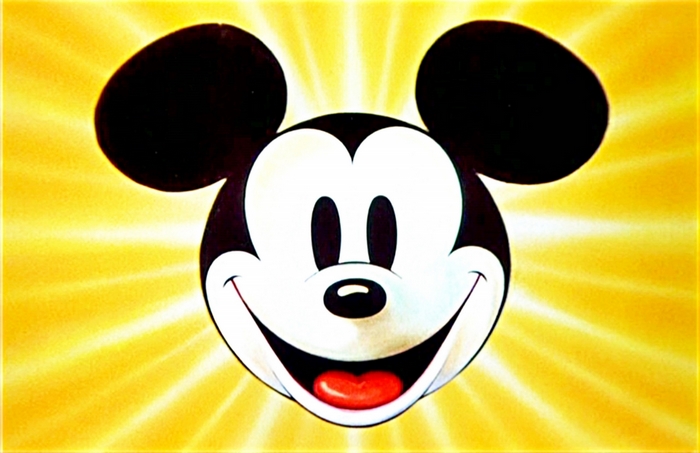 Mickey Mouse smiling against a yellow sunburst