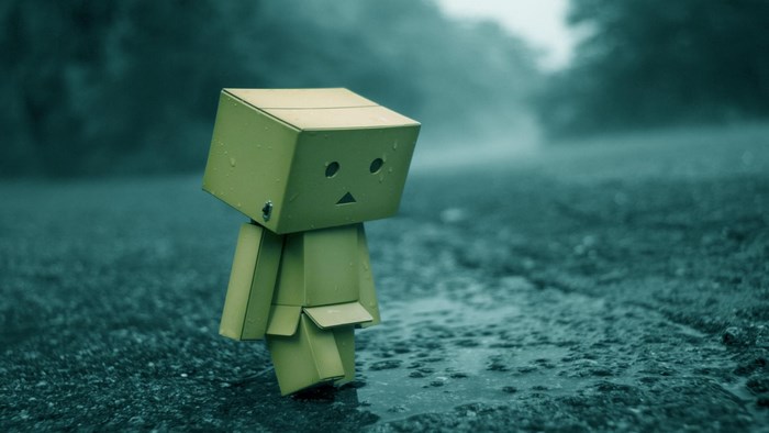 Sad cardboard robot in the rain