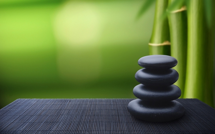 Stacked stones on bamboo mat with bamboo background