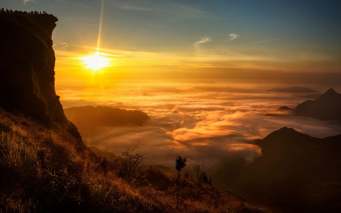 Sunrise over a sea of clouds from a mountain cliff