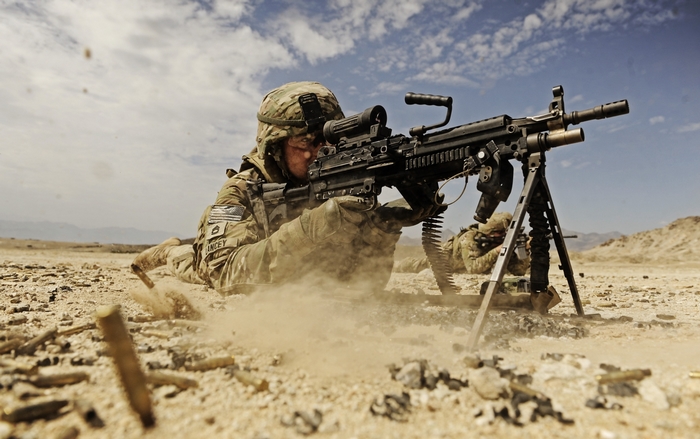US Army soldier firing machine gun in desert