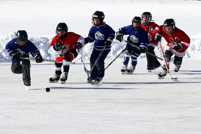 Children playing hockey on a frozen outdoor rink
