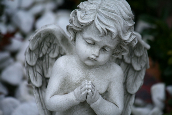 Stone angel statue praying outdoors