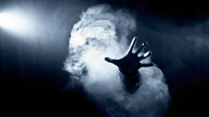 Hand reaching out of smoke with spotlight