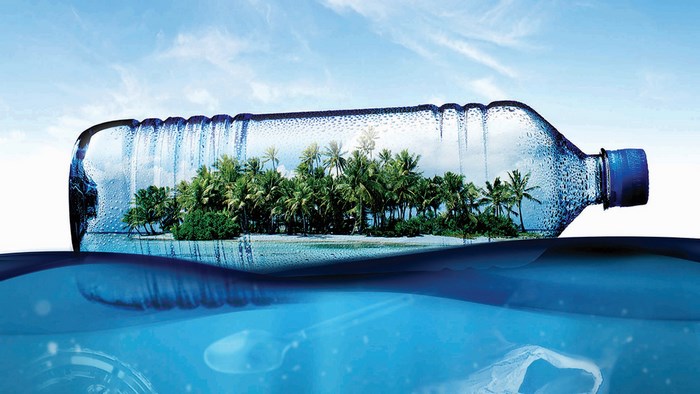 Plastic bottle with island inside floating in ocean
