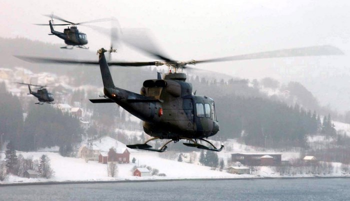 Bell UH-1 Helicopters in Flight Over Snowy Landscape