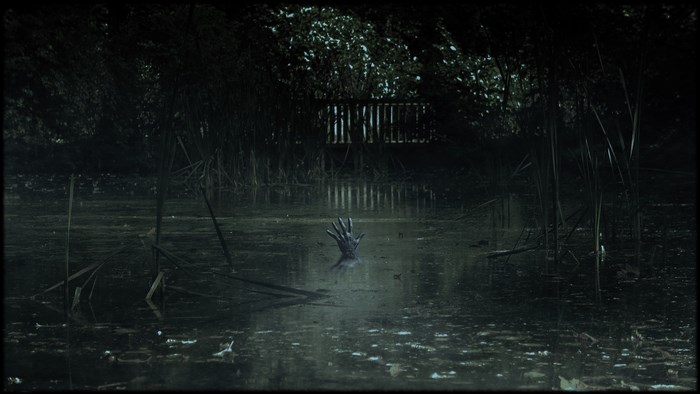 Creepy hand emerging from murky water