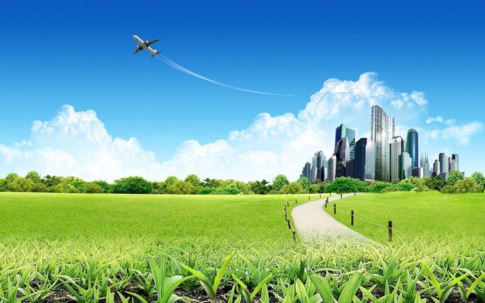 Airplane flying over a green field and cityscape