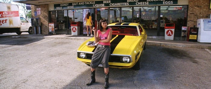 Stuntman Mike's car and woman in front of a store