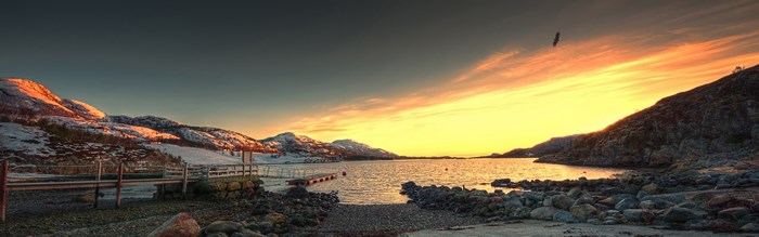 Panoramic view of a lake at sunset with snow-capped mountains