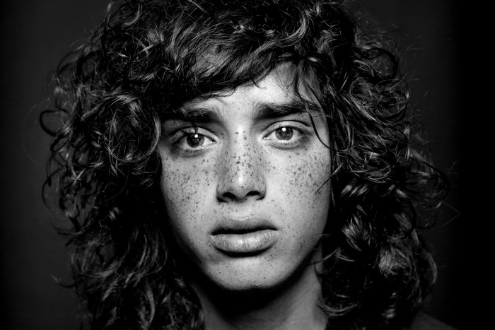 Black and white portrait of a young person with freckles and curly hair